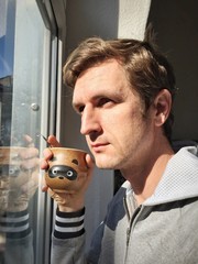 Man at window with cup of of coffee