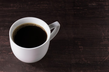Cup of freshly brewed black coffee on wooden table