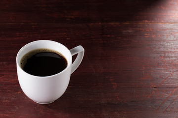 Cup of freshly brewed black coffee on wooden table