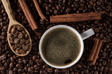 Cup French coffee with cinnamon sticks and background of beans