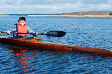 The boy rowing in a kayak on the river