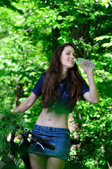 The girl in the woods on a bike drinking water