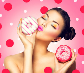 Beauty fashion model girl taking colorful donuts over pink