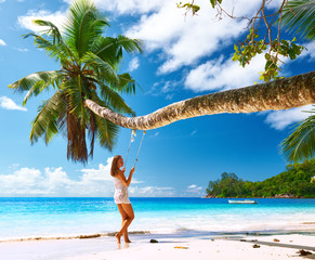 Woman in blue dress swinging at beach
