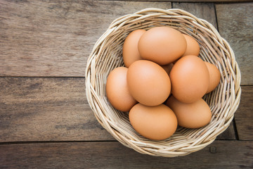 Eggs in wicker basket on old wooden table