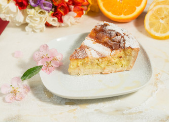 Fetta di pastiera napoletana con fiori e agrumi