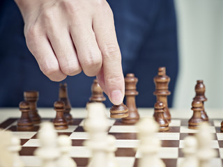 hand of a man moving a pawn to start a chess match