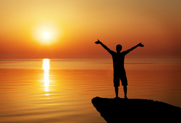 Fototapeta premium Silhouette of a man on a mountain top on sunset background