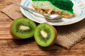 Kiwi fruit cut in half in front of green cake on jute cloth