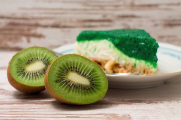 Fototapeta na wymiar Kiwi fruit cut in half on white board in front of green cake