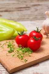 Three tomatoes and cress on wooden board