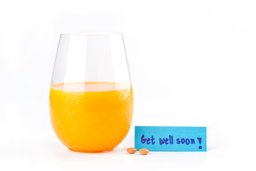 Fresh orange juice with pills and get well soon note on white ba