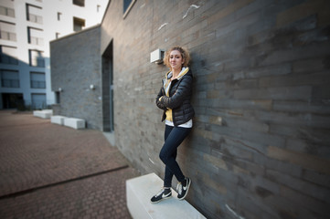 Young woman stands near  wall in the city.