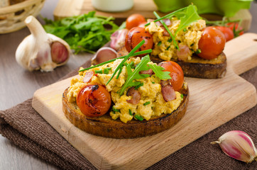 Scrambled eggs witch bacon, herbs and tomato