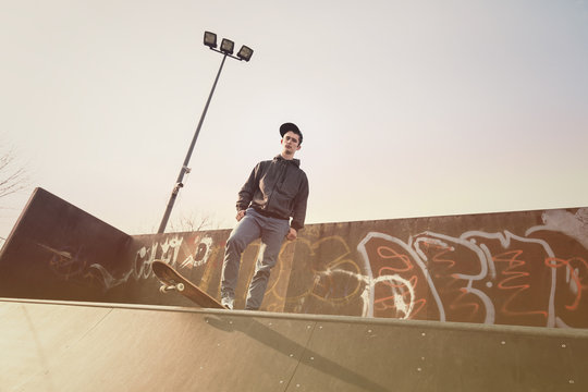 Young man with a skatboard standing on top of the skate ramp