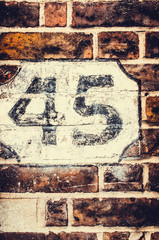Number 45 painted on brick wall with retro filter applied