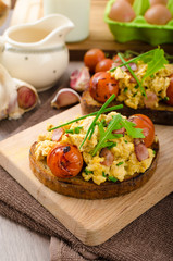 Scrambled eggs witch bacon, herbs and tomato