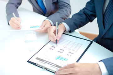 Two businessmen looking at report and having a discussion in off