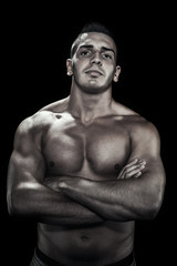 Fototapeta na wymiar Low light portrait of bodybuilder over black background