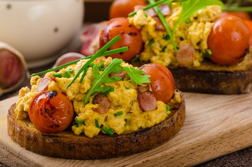 Scrambled eggs witch bacon, herbs and tomato