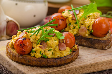 Scrambled eggs witch bacon, herbs and tomato