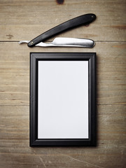 Straight razor and picture frame on wood desk