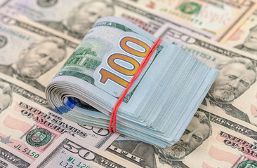 Folded dollar bills wrapped by rubber lying over  banknotes