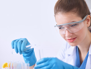 Fototapeta premium Woman researcher is surrounded by medical vials and flasks