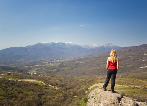 girl standing on a cliff in the mountains