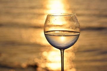 glass with white wine above sunset sea ocean
