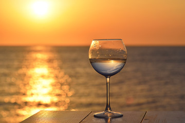 glass with white wine above sunset sea ocean