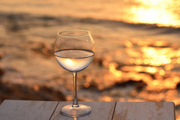 Romantic glass of wine sitting on the beach at colorful sunset Glasses of white wine against sunset, white wine on the sky