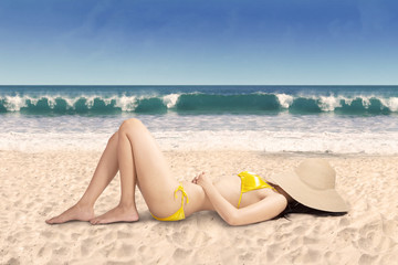 Fototapeta na wymiar Sexy woman in bikini relaxing on beach, shot on tropical beach