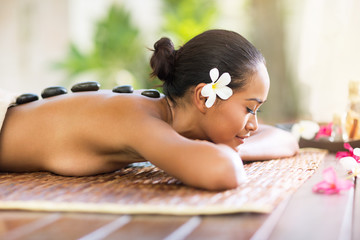 Balinese woman having hot stone massage in spa salon