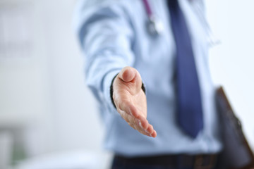 Male doctor extending his hand for a handshake in clinic
