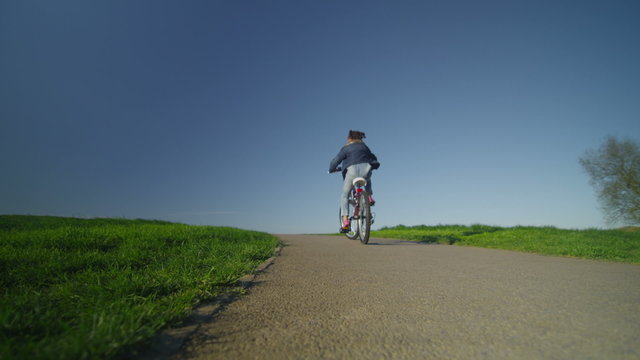 Little child riding a bike into the distance on a path