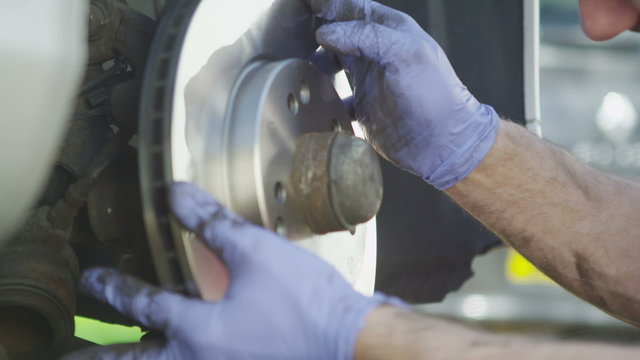 Mechanic replacing a brake disc in slow motion