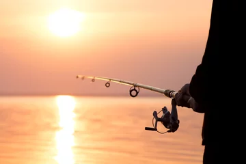 Fotobehang young girl fishing at sunset near the sea © fantom_rd