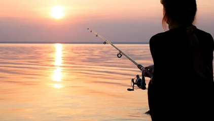 Stof per meter jong meisje vissen bij zonsondergang in de buurt van de zee © fantom_rd