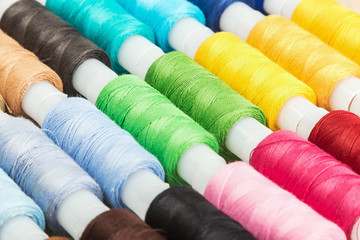 Multicolor sewing threads on wooden background
