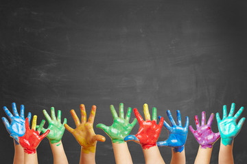Bunte Kinderhände mit Fingerfarbe vor Tafel