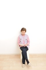 何もないシンプルな部屋と高齢者のアジア人女性