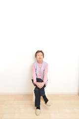 何もないシンプルな部屋と高齢者のアジア人女性