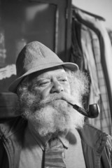 portrait of an old man with a long beard smoking a pipe