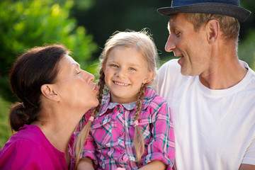 Mädchen mit Vater und Oma im Garten, Kuss