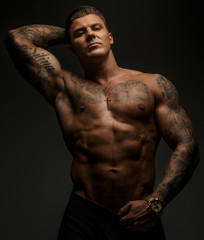 Fototapeta premium Tattooed muscular guy posing on gray background