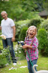 Mädchen mit Gartenschlauch hat Spaß im Garten