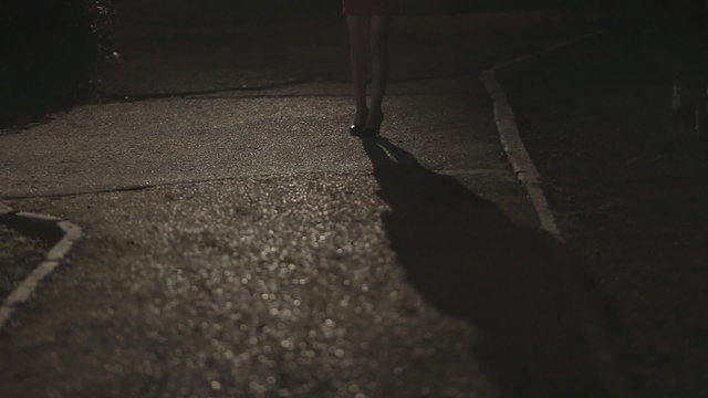 Shadow and the girl's legs in high heels standing in the dark