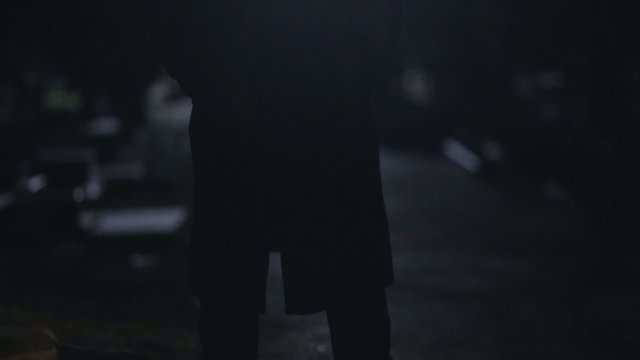 Portrait of mysterious man in black cloak and hat standing at
