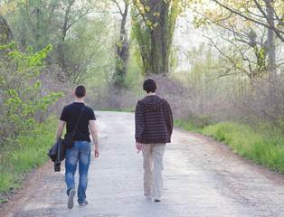 Two male adult friends walking in the nature on sunny spring day